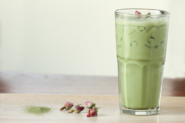 green tea latte decorated with dried rose on wooden background