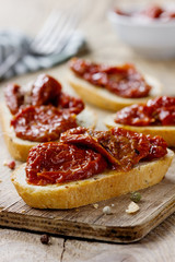 Sun-dried tomatoes and fresh bread on a wooden kitchen board