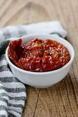 Sun-dried tomatoes in a small bowl on a wooden kitchen board