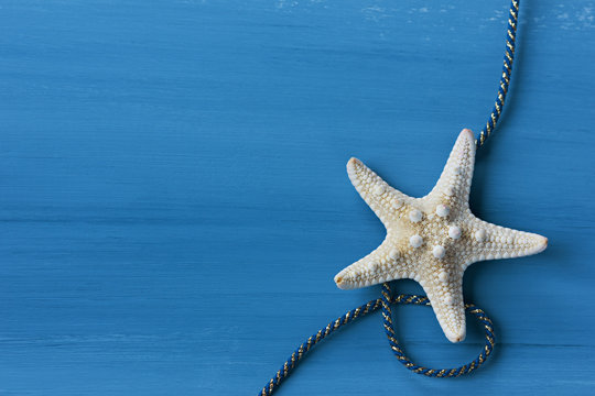 Fototapeta Starfish with cable against a blue colored wood background