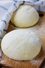 Dough balls covered with cloth on a wooden rustic kitchen board