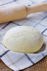 Pizza dough with rolling pin on a linen napkin