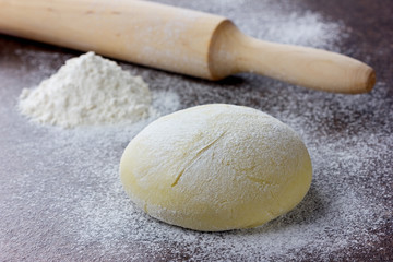 Fototapeta na wymiar Dough with rolling pin and flour on a stone surface