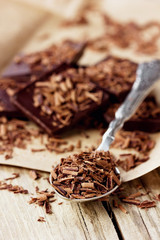 Grated dark chocolate in a spoon on kraft paper, macro shot
