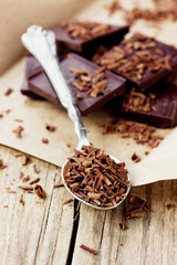 Grated dark chocolate in a spoon on kraft paper, macro shot