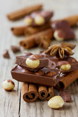 Milk chocolate slices with nuts, cinnamon sticks and anise star