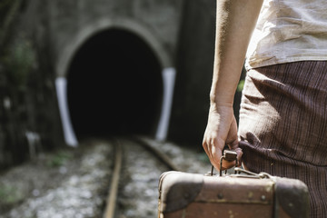 Woman and vintage suitcase on railway road