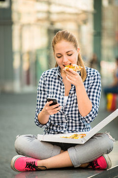Teenager eating pizza looking in phone