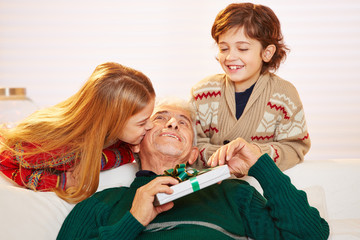 Mädchen küsst Opa mit Geschenk an Weihnachten