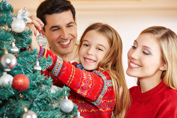 Eltern und Kind schmücken Weihnachtsbaum zu Weihnachten