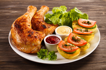 Barbecued chicken legs with French fries and vegetables