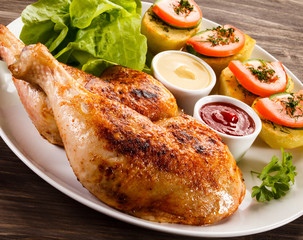 Barbecued chicken legs with French fries and vegetables