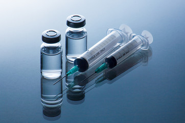 medical ampoules and syringe on blue background
