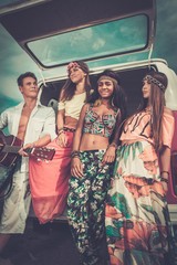 Fototapeta na wymiar Multi-ethnic hippie friends with guitar on a road trip