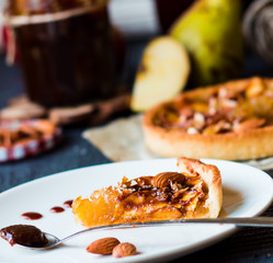 piece of apple tart on a round plate, spoon caramel