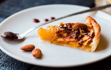 piece of apple tart on a round plate, spoon caramel