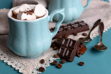 Cup of coffee with marshmallow and chocolate on wooden table
