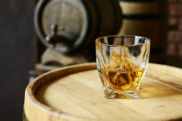 Glass of brandy in cellar with old barrels