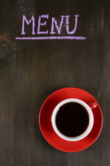 Inscription menu on wooden board with cup of tea close-up