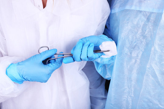 Surgeon's hands holding clip with napkin close up