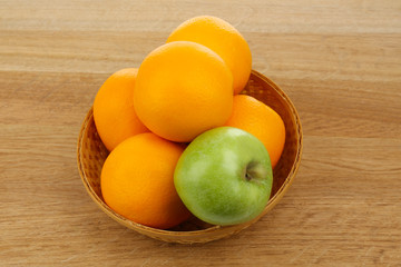 Juicy oranges and apple on wooden table, close-up