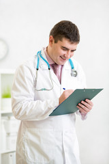 Portrait of smiling male doctor with clipboard at office