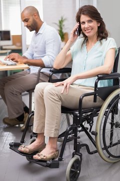 Smiling businesswoman in wheelchair on the phone