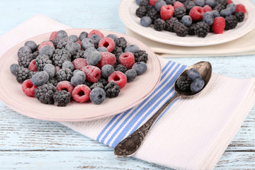 Iced berries on plate, on color wooden background