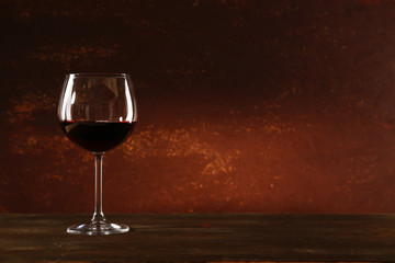Goblet of red wine on wooden table on wooden wall background