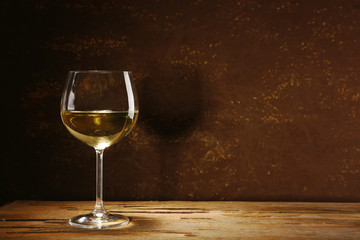 Goblet of white wine on wooden table on wooden wall background