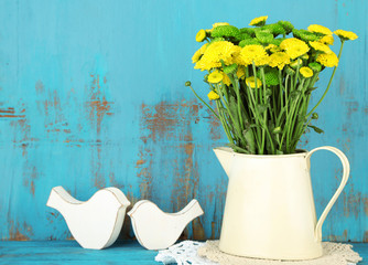 Yellow and green flowers in decorative jug