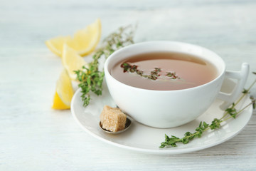 Cup of tasty herbal tea with thyme and lemon on wooden table