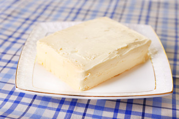 Fresh butter on plate, on table background