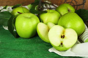 Ripe apples in metal basket with napkin on wooden background