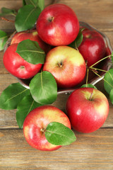 Ripe apples in bowl on wooden background