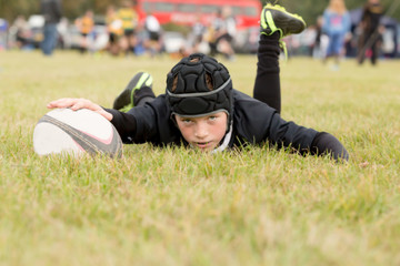 Young boy on the ground with a rugby ball