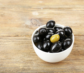 Individuality concept. Olive in bowl on wooden table