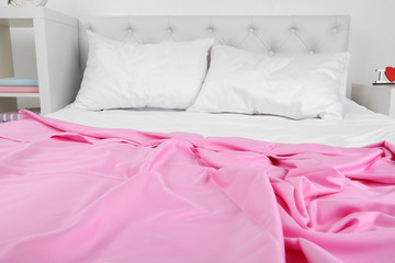 Fototapeta na wymiar Crumpled pink linen on bed
