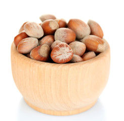 Obraz premium Hazelnuts in wooden bowl isolated on white