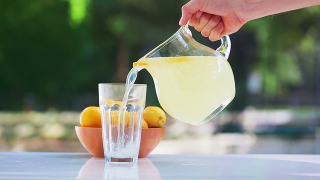 Fresh lemonade pouring into a glass outside