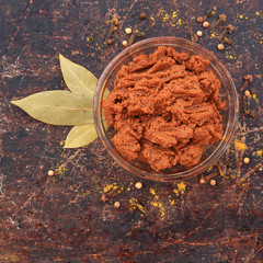 Curry paste in glass bowl with various spices