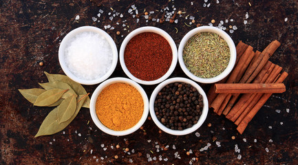 Various spices, herbs and seasonings on brown rustic background