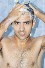 Young cute man washing head in bathroom