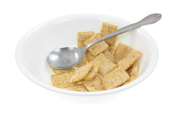 A bowl with leftover whole wheat cereal and spoon