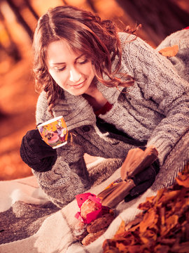 young woman reading book and drinking tea at fall forest