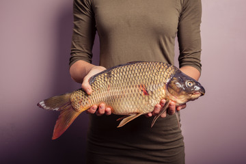 Young woman holding a carp