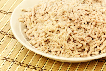 Minced meat from chicken on a plate on wood table mat