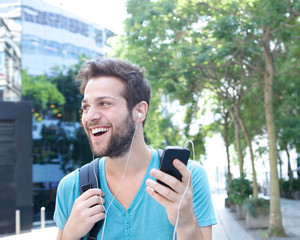 Young man smiling with mobile phone and earphones