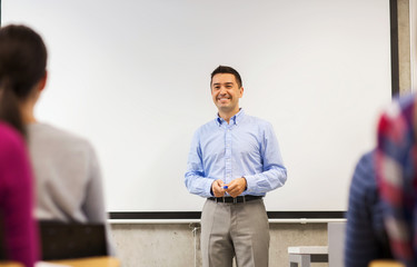 group of students and smiling teacher in classroom