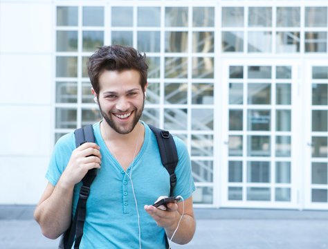 Smiling young man with mobile phone and backpack